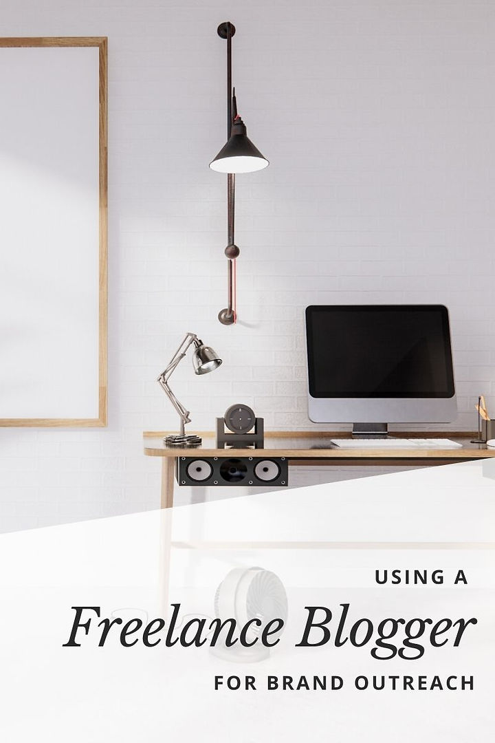 The benefits of using a freelance blogger for your small business. A desk with a desktop computer on it and a lamp hanging from the wall.
