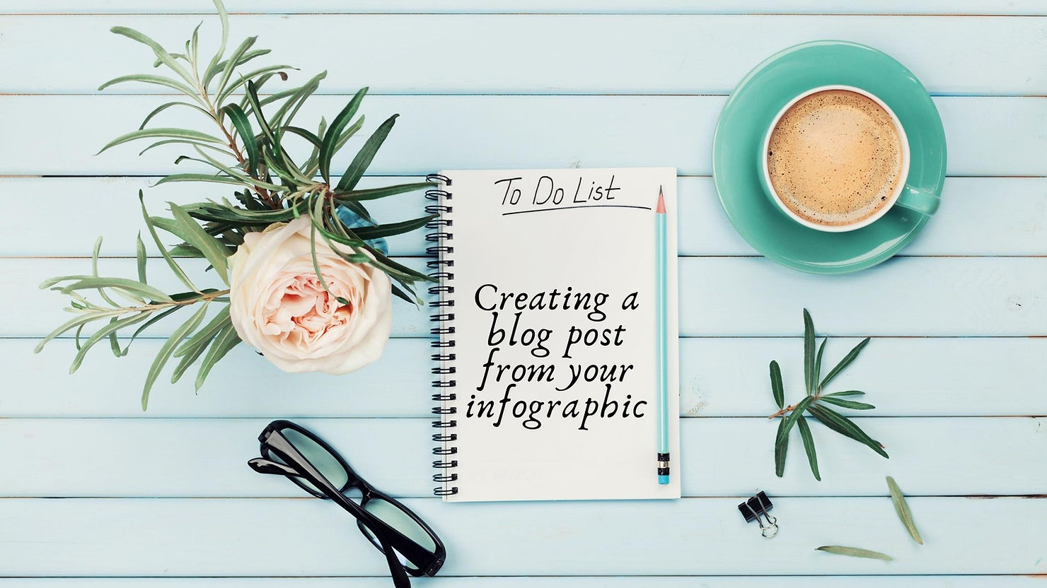 A blue wooden background with a beautiful flower, glasses, and a cup of coffee with a notebook on it that says to do list.